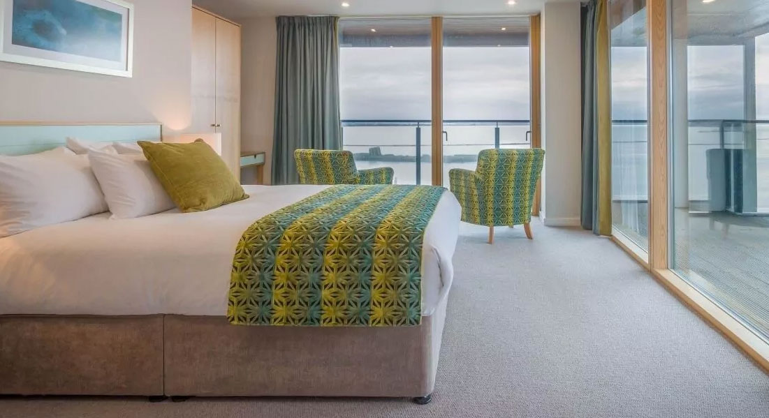 塔尔博特套房（Talbot Suites）的一间高端现代卧室，从地板到天花板的窗户都能看到宽阔的河流景色。