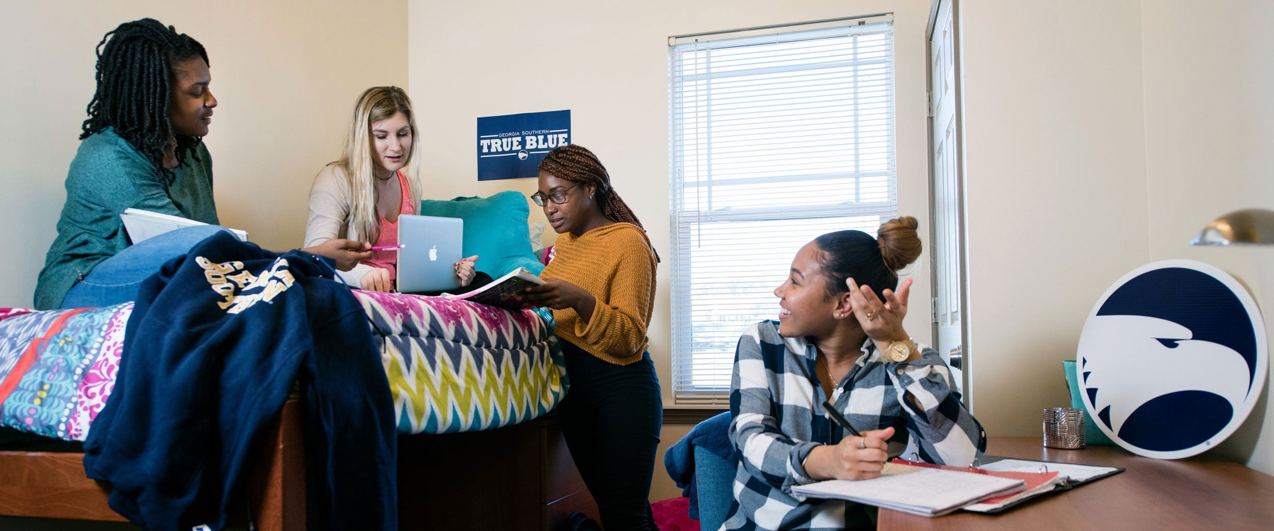 Four students engage in a study session in a Georgia Southern dorm room