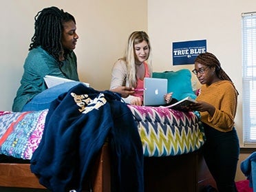 Three students gather to study in a dorm room on the Armstrong Campus.
