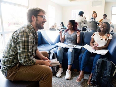 An advisor and Georgia Southern students sit in a common area for a Residential Learning Community group meeting