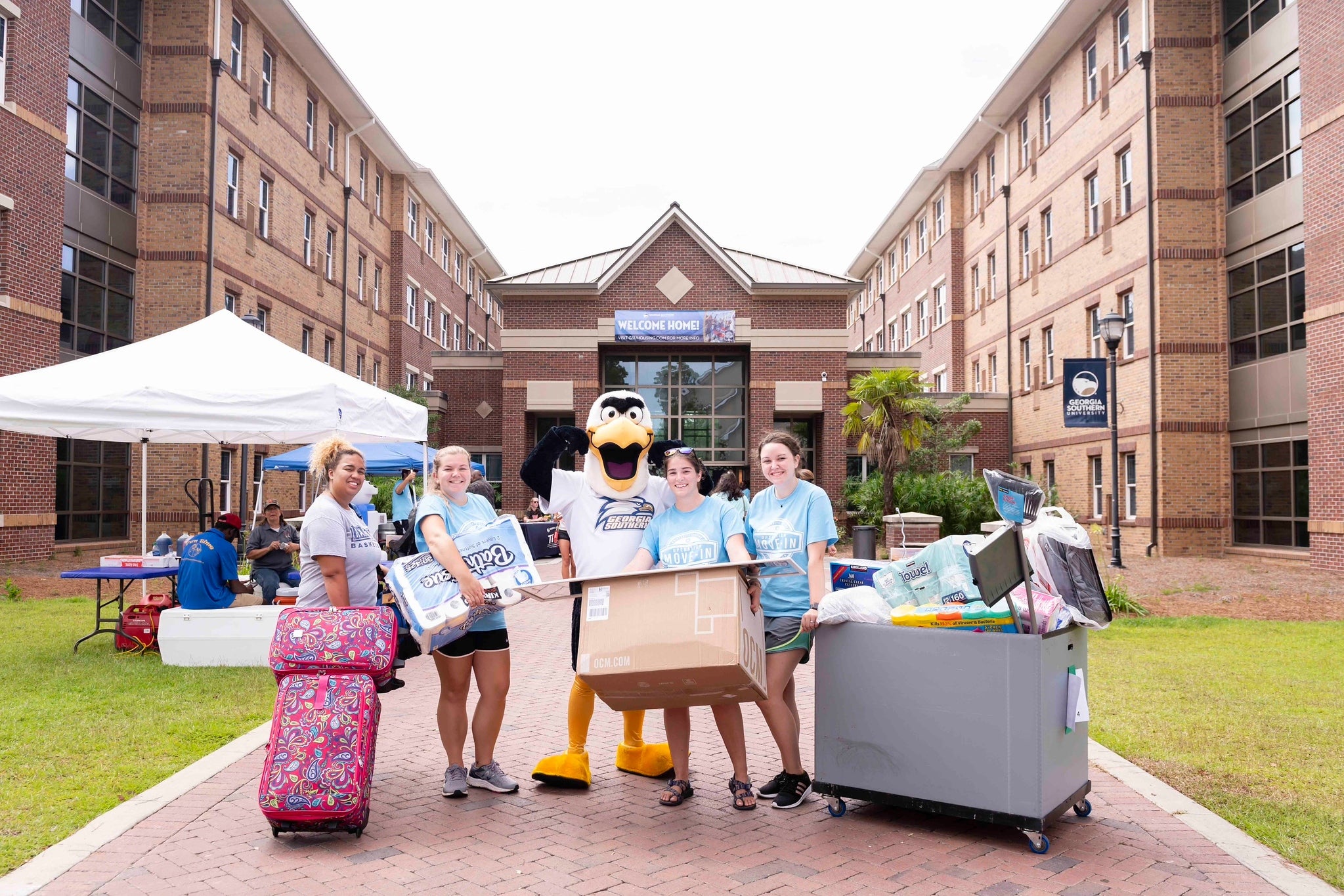 Gus and students in front of a university housing area