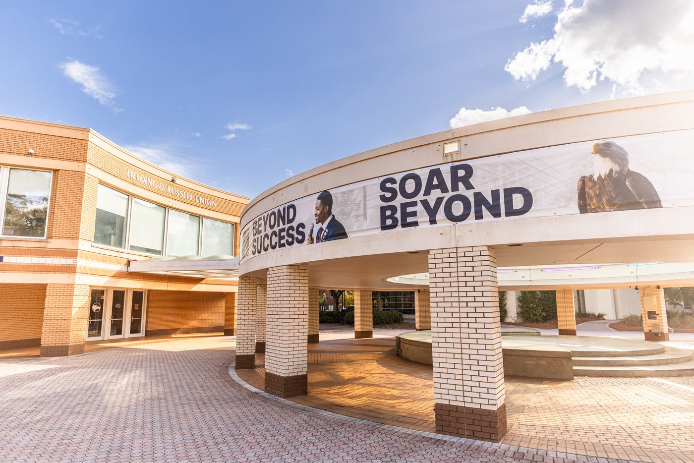 Georgia Southern banner wraps around Russell Union rotunda reading 'Soar Beyond Success' with a student and bald eagle.