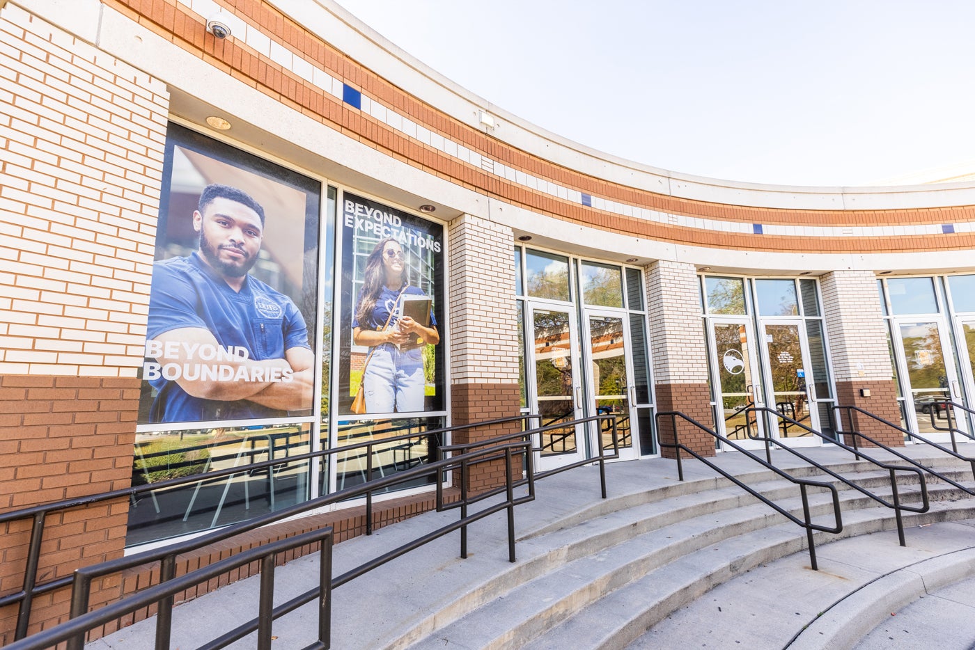 Exterior of the Russell Union with large Soar Beyond posters reading 'Beyond Boundaries' and 'Beyond Expectations' showing confident students.