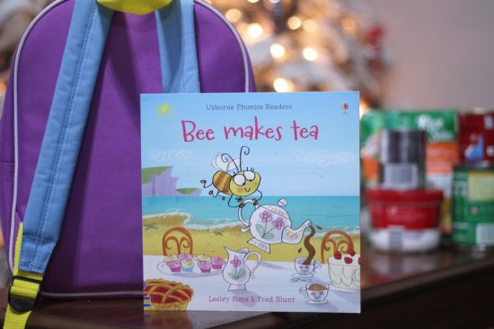 A book for children titled Bee Makes Tea and a child's backpack.