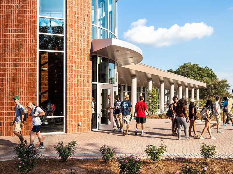 Exterior of the Dining Commons on Georgia Southern campus with students walking around and talking.