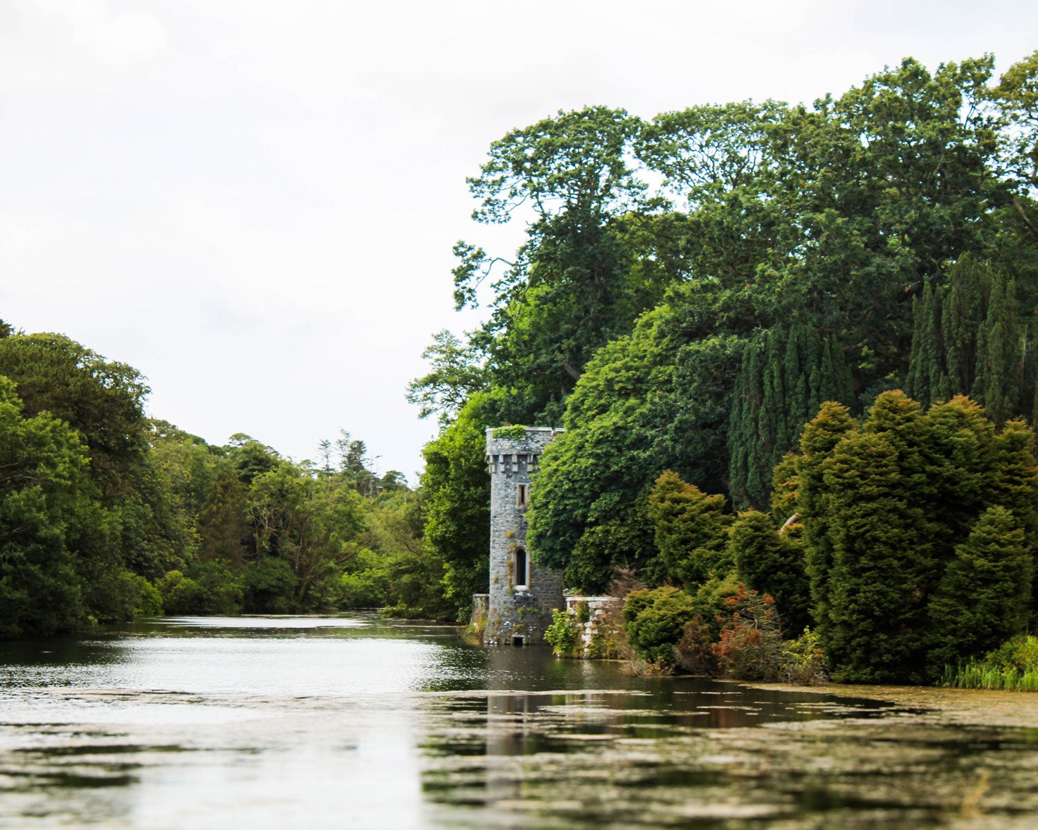 Beautiful river scene in Ireland with lots of greenery around a small castle.