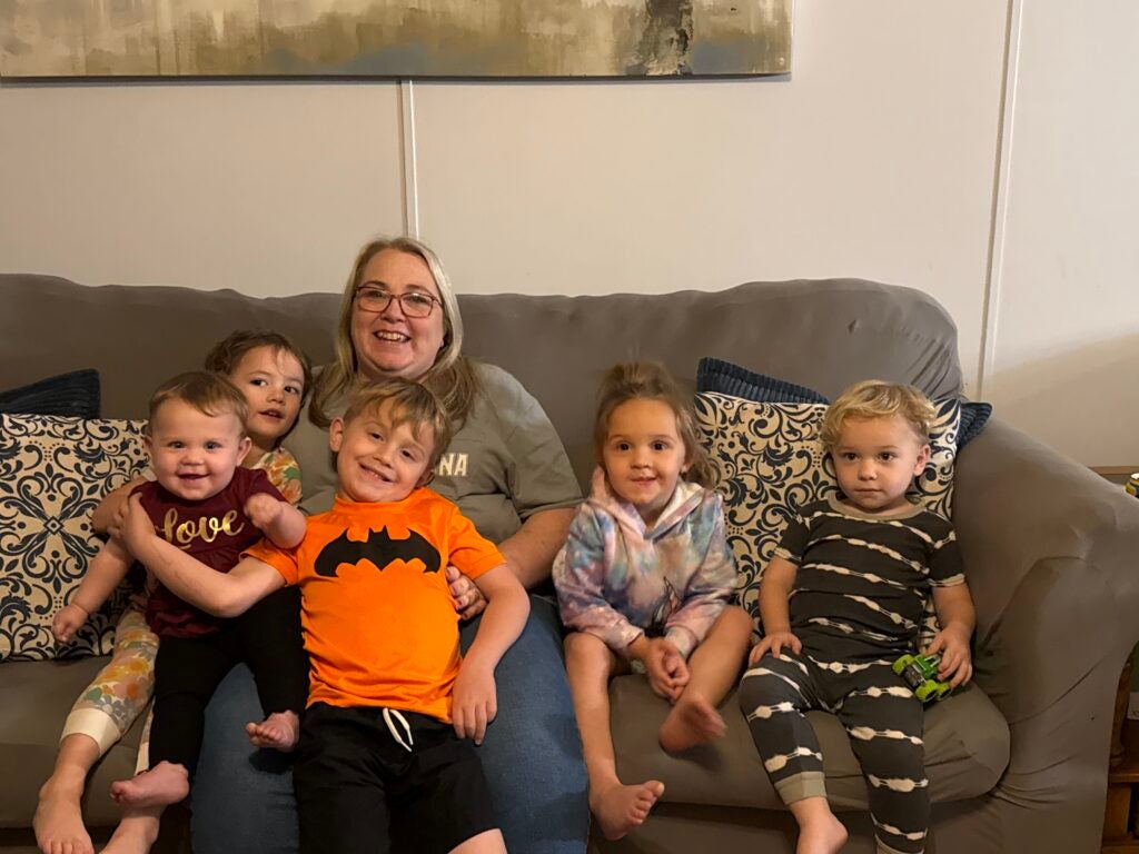Melissa Miles sits on a couch surrounded by her grandchildren.
