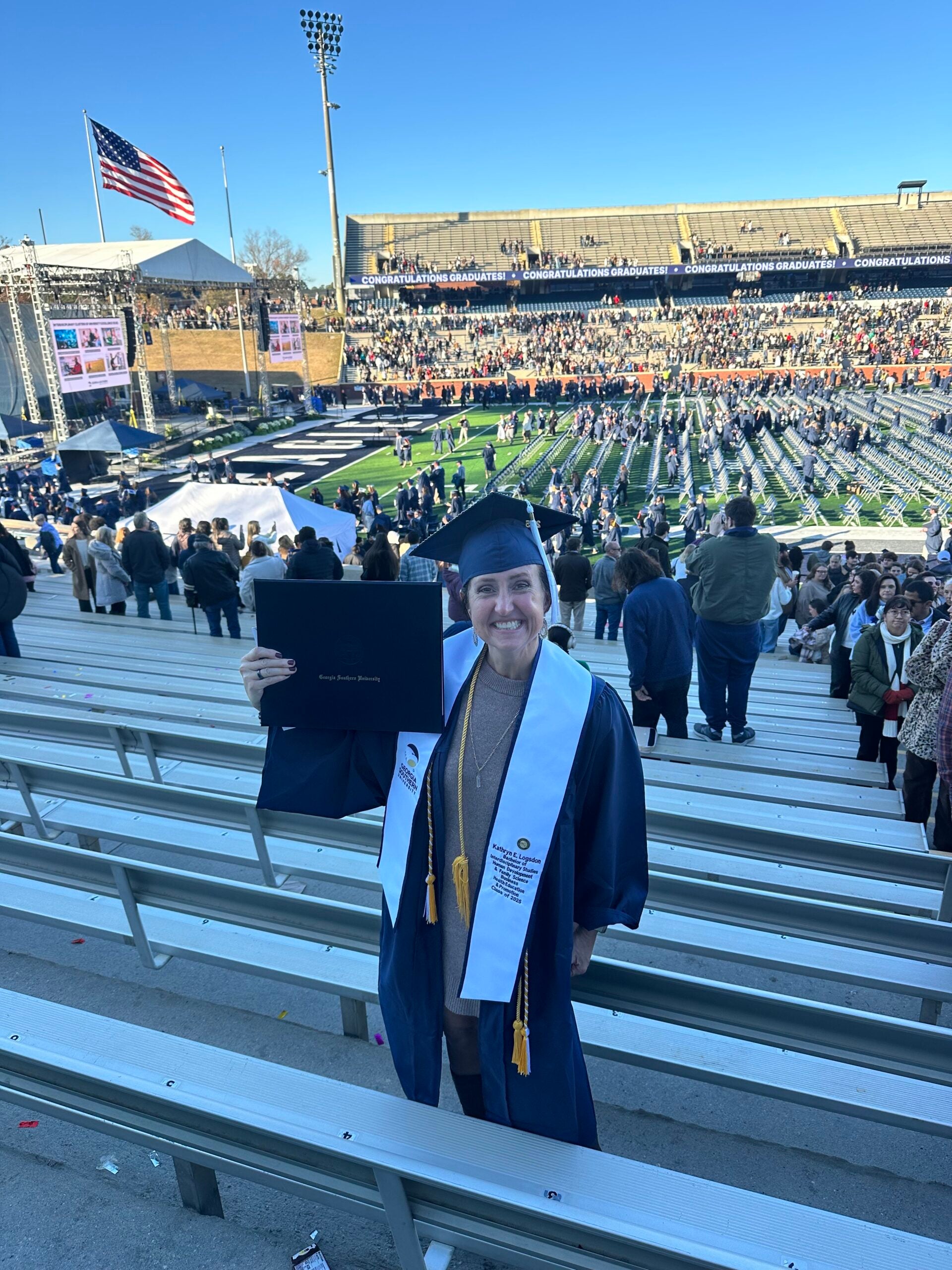 A woman with short brown hair poses with her diploma at Georgia Southern's Paulson Stadium