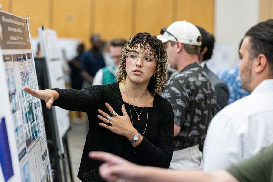 Women in curly hair explaining her research in an expo