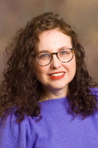 Amy Potter wearing glasses and a purple sweater