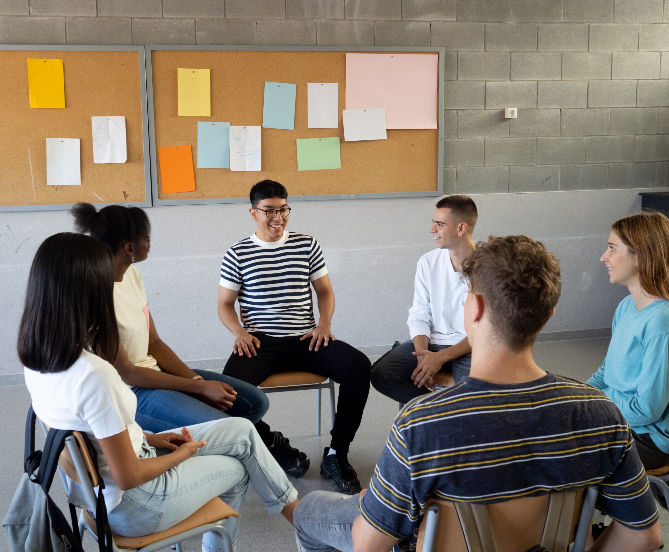 Group of diverse teenage students talking to each other sitting in a circle in a classroom at a school. High quality photo