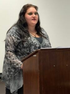 Annelise Hughes stands at a lecture while debating