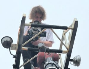 A student operates a camera on top of a firetruck ladder