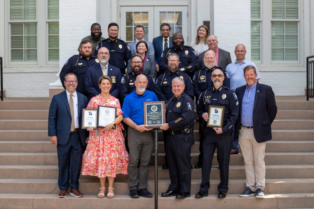 Members of Georgia Southern University leadership and the University Police Department stand on the steps of the Marvin Pittman Administration Building, smiling and holding plaques identifying the certifications and awards noted in the story.