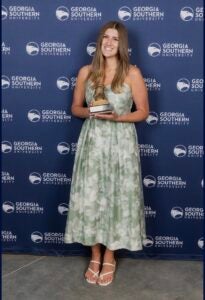 Lily Pavliscsak smiles while holding a Georgia Southern University trophy.