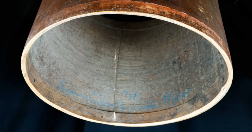 Inside view of a large Revolutionary War drum with blue handwriting along the inner wall that reads, "Benjamin Clark."