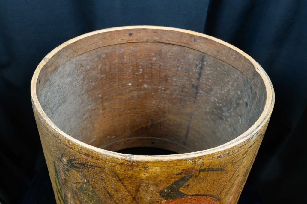 Open, weathered Revolutionary War drum seen from above against a dark background, showing grain and worn finish.