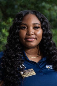 Portrait of Mariyah Terry wearing a Georgia Southern University Southern Ambassador name badge, outdoors.